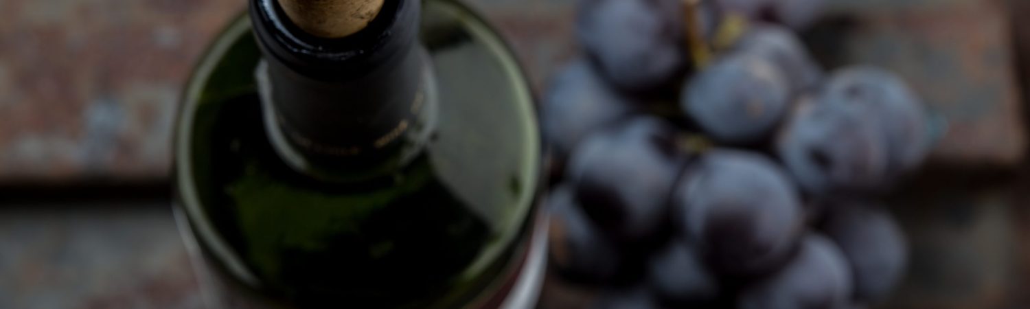 Top view of red wine bottle. Macro, selective focus on wine cork. Wine bottle, glass and grape on vintage background. Copi space, wine concept.